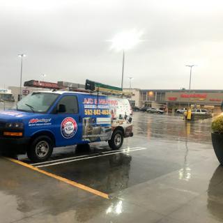 A branded van parked in a rainy shopping center parking lot.