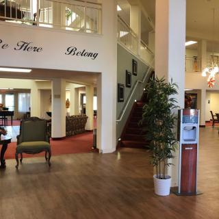 A spacious lobby with elegant furniture, potted plants, and a staircase leading to an upper level.