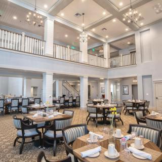 A spacious and elegantly designed dining area with neatly set tables and soft lighting.