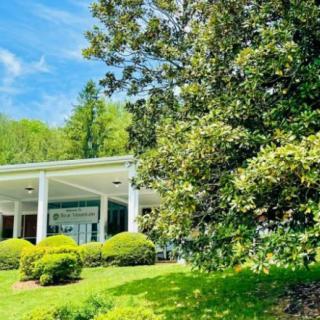 A beautiful building surrounded by lush greenery and trees under a clear blue sky.