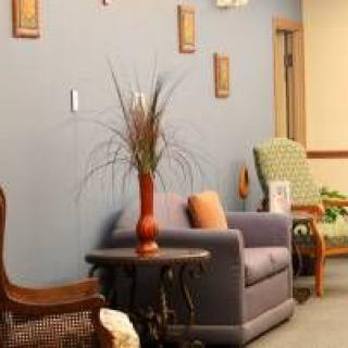 A cozy waiting area featuring a sofa, chairs, and decorative elements on the wall.