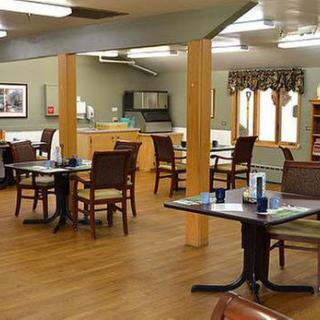 A dining area with neatly arranged tables and chairs on a wooden floor.