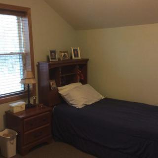 A cozy bedroom with a single bed and wooden furniture.