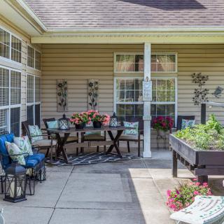 A cozy patio with a dining table set, surrounded by plants and decorative elements.