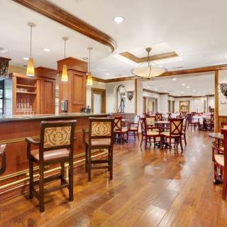 Elegant restaurant interior with a spacious bar and dining area featuring wooden floors and classic decor.