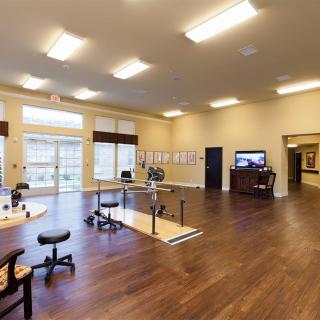 A spacious room with wooden flooring, equipped with furniture and ample lighting.