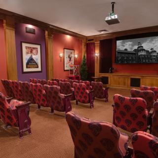 A luxurious home theater with plush seating and a large screen.