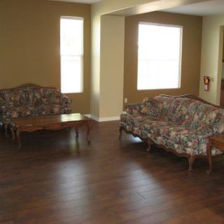A living room with a hardwood floor, featuring patterned sofas and a wooden coffee table.