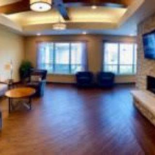 A spacious living room with comfortable seating, a fireplace, and large windows.