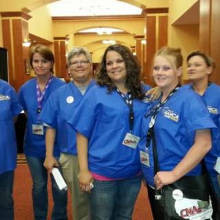 A group of people wearing blue shirts posing indoors.