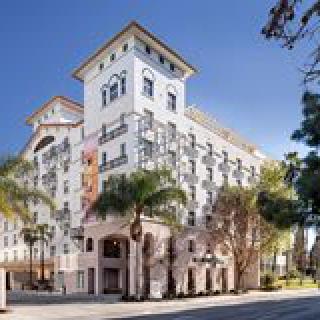 A view of a large hotel building with palm trees in an urban setting.