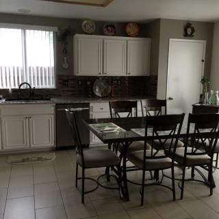 A modern kitchen with a dining table and chairs, featuring white cabinets and a tiled floor.