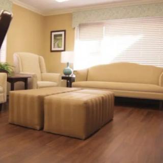 A well-lit living room featuring a cozy sofa, armchair, and matching ottomans on a wooden floor.