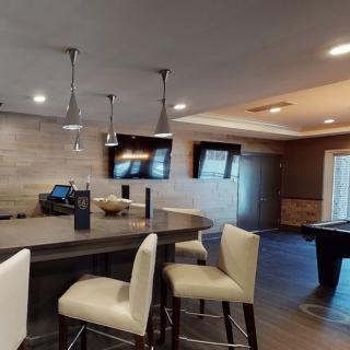 A modern and stylish open living area with a kitchen island, bar stools, and a pool table.