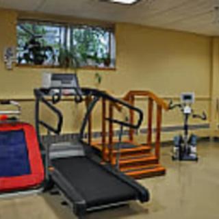 A room with various exercise and rehabilitation equipment, including a treadmill.