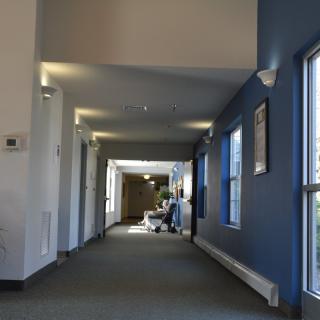 A well-lit hallway with blue walls and large windows on one side.