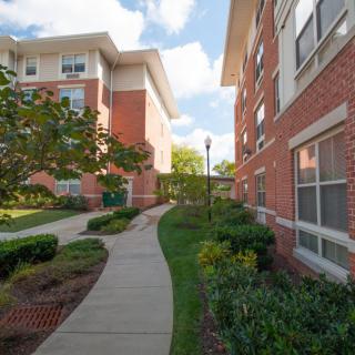 A well-maintained apartment complex with a landscaped pathway and brick exterior.