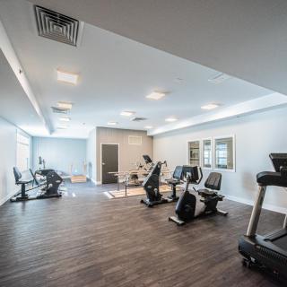 An empty gym with modern exercise equipment, including treadmills and stationary bikes.