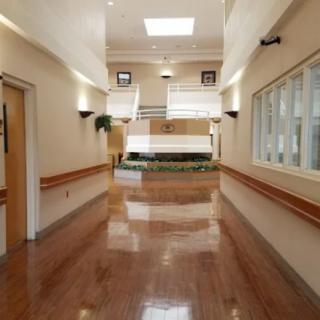 A clean and modern hallway in a building, featuring large windows and bright lighting.