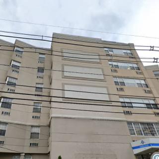 A multi-story apartment building with a concrete facade and multiple windows.