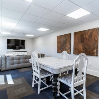 A modern conference room with a white table, matching chairs, and abstract artwork on the walls.