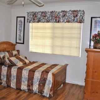 A cozy bedroom with a wooden bed, dresser, and patterned bedding.