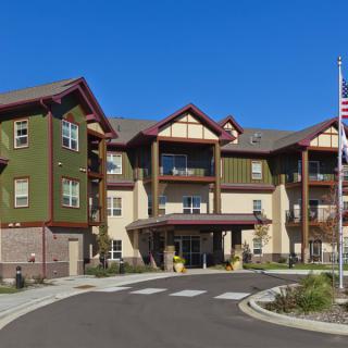 A sunny day view of a residential senior living facility with landscaped surroundings.