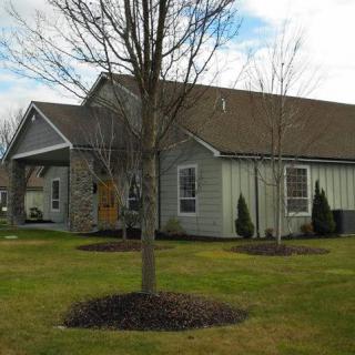 A suburban house with a lawn and trees in the yard.