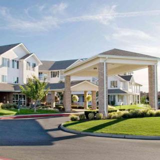A modern residential building with well-maintained landscaping under a clear blue sky.