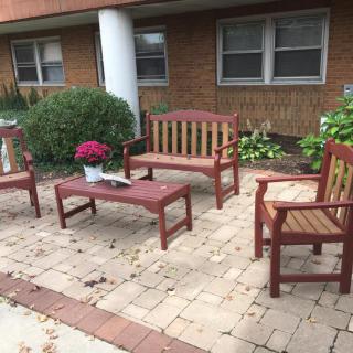 A cozy brick patio with wooden benches, a table, and a potted plant.