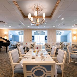 A beautifully arranged dining room featuring elegant furniture, a piano, and bright lighting.