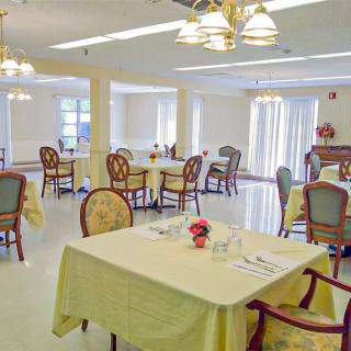 An elegant dining room with neatly arranged tables and chairs, featuring soft lighting and a warm ambiance.