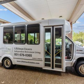 A white shuttle bus parked under a covered area, likely used for transportation services.