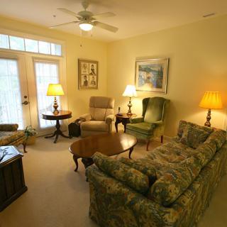 A cozy living room with elegant furnishings, including a sofa, armchairs, and warm lighting.