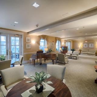 A spacious and cozy lounge area featuring a piano, various seating arrangements, and large windows.