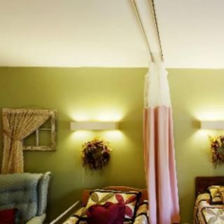 A shared hospital room with two beds separated by a curtain and decorated walls.