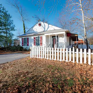 A charming house with a white picket fence surrounded by autumn leaves.