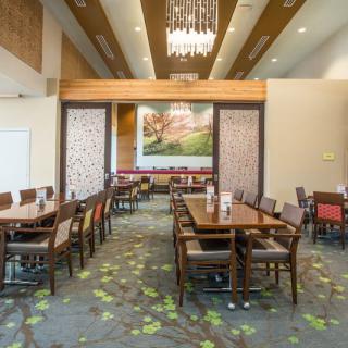 A modern dining area with neatly arranged tables and chairs, featuring stylish decor and a chandelier.