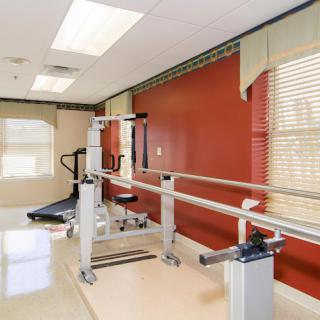 A well-lit rehabilitation room featuring parallel bars for physical therapy exercises.