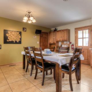 A cozy dining room with a wooden table and chairs, decorated with artwork and featuring a warm light fixture.