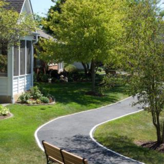 A peaceful garden pathway winding through a lush, landscaped yard next to a house.
