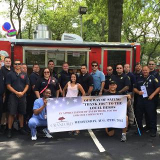 A group of firefighters and community members holding a banner during an outdoor event.