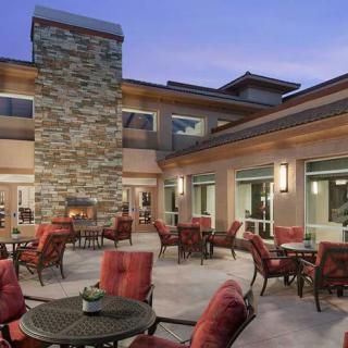 An outdoor patio with seating and a fireplace at dusk.