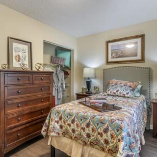 A cozy bedroom with a bed, dresser, and decorative elements.
