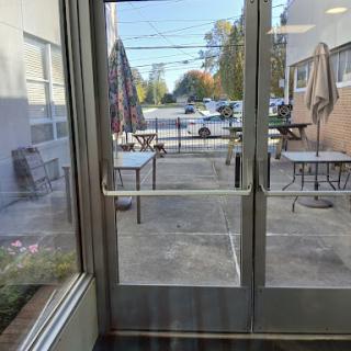 A view through double doors leading to an outdoor seating area with tables.