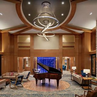 A luxurious lounge interior featuring a grand piano, elegant furniture, and a modern chandelier.