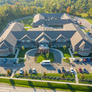An aerial view of a large, symmetrical building with a parking lot and surrounding greenery.