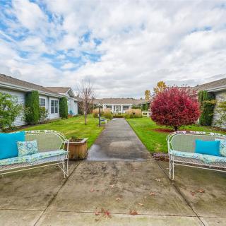 A serene courtyard featuring benches and lush greenery under a cloudy sky.