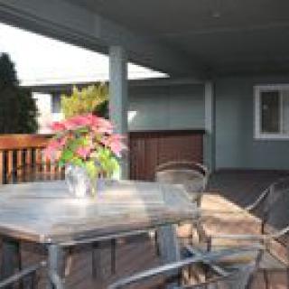 An outdoor patio with a table and chairs, featuring a vase of flowers as a centerpiece.