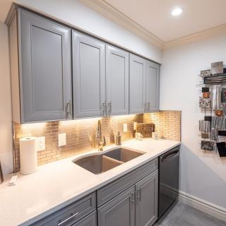 A modern kitchen with gray cabinets, a sleek countertop, and ambient lighting.